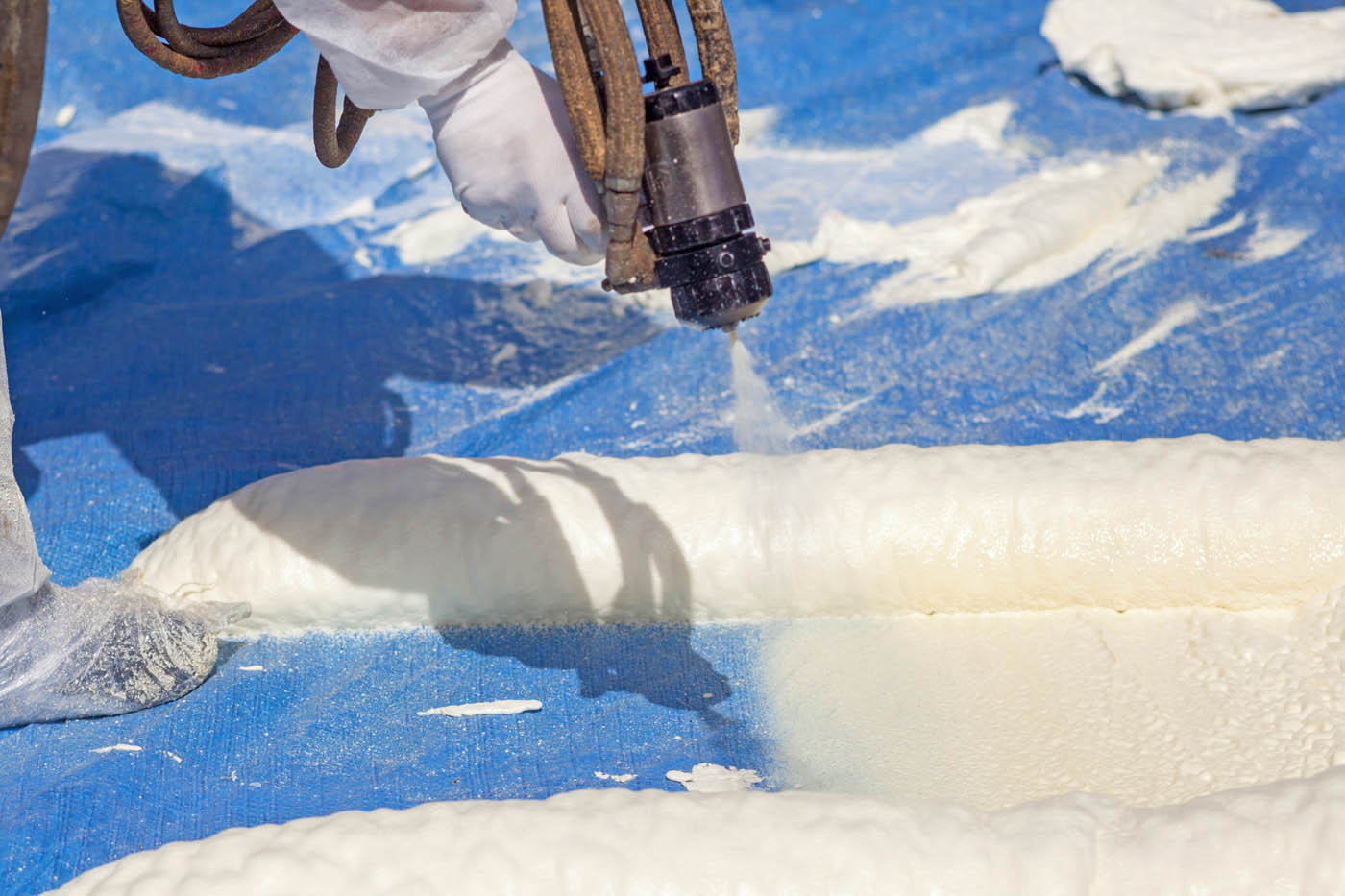 Spray foam being demonstrated on a blue mat, contact iFoam one of the top spray insulation companies.